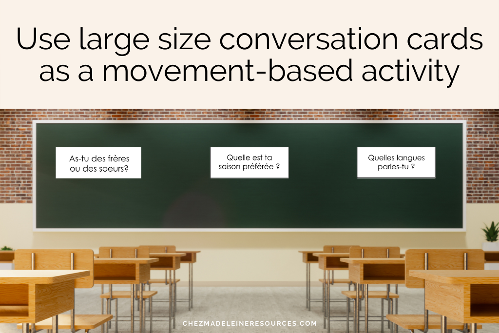 An image of an empty classroom with only desks and a blackboard. On the blacboard are posted three large size conversation cards. The text reads "use large size conversation cards as a movement-based activity"